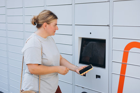Parcel delivery machine. Mail delivery and post service concept. Happy smiling woman with phone at...