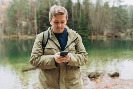 Travel backpacker standing with phone near the majestic lake. Travel, adventure. Concept of an...