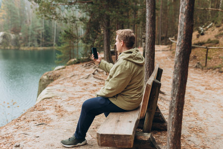 30s happy man uses a telephone for take pictures, make selfies and video calls friends on nature background. Travel and wanderlust conceptの写真素材