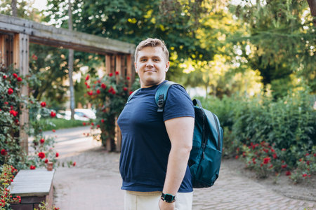 Young happy smiling man walk in green city park outdoors on nature. Urban lifestyle leisure concept. High quality photo.の写真素材