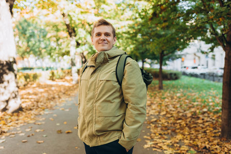 Calm happy 30s Man Relaxing in Autumn Park Outdoors. Traveler. Falling time. Smiling man in casual...