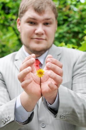 Man holding or protecting yellow flower (dandelion) の写真素材
