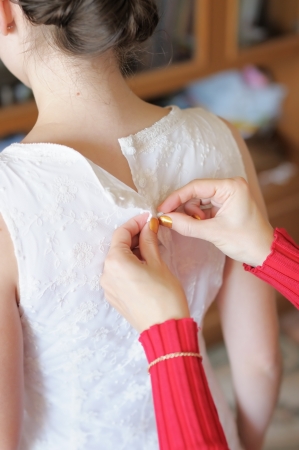 Helping the bride to put her wedding dress onの写真素材