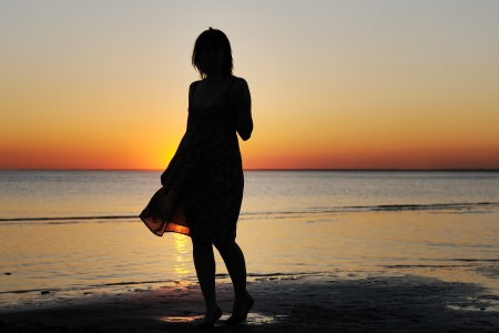 Portrait of young woman as silhouette by the seaの写真素材