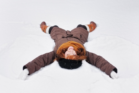 Winter fun - snow angel -  young beautiful woman playing in snowの写真素材