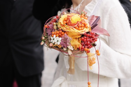 Bride holding beautiful orange wedding flowers bouquetの写真素材