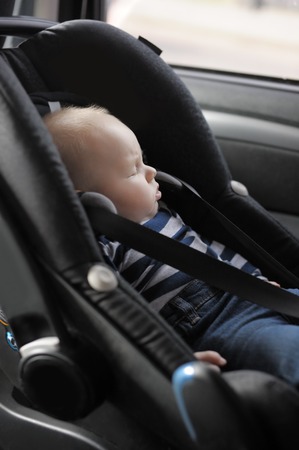 Little baby boy with close eyes in car seatの写真素材