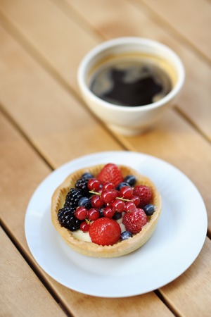 Custard fruit tart and cup of coffee in the outdoors cafe の写真素材