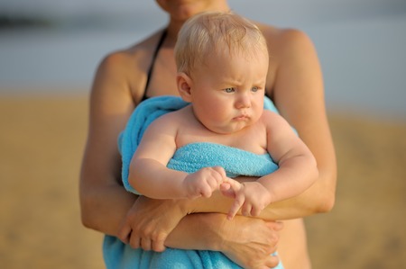Middle age woman with little baby boy on beach の写真素材