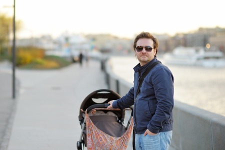 Middle age man walking with baby strollerの写真素材