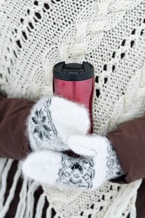 Metallic tumbler with hot beverage in woman hands