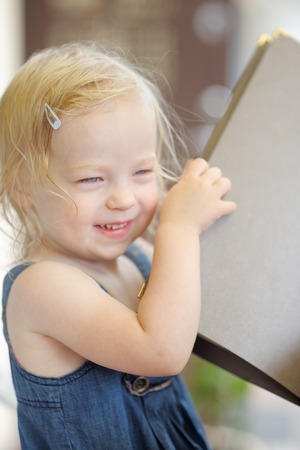 Happy little girl holding menu or bookの写真素材