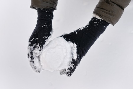Woman holding snowball in her handsの写真素材