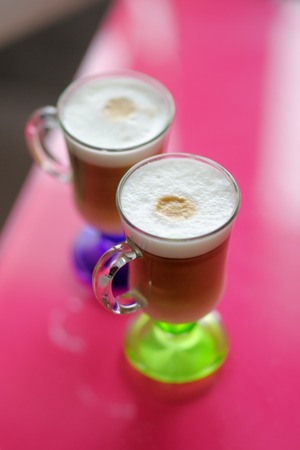Two glass cups of coffee standing on bright tableの写真素材