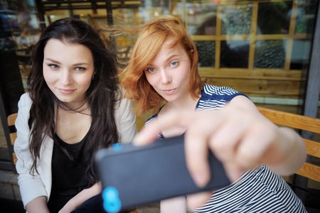 Two young girls taking a self portrait (selfie) with smart phone