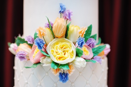 Part of  white wedding or birthday cake decorated with cream colorful flowersの写真素材