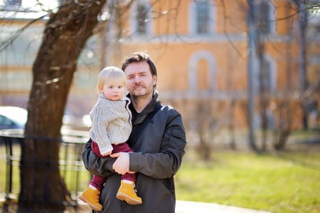 Middle age father with his toddler son walking and playing outdoors at the warm spring dayの写真素材