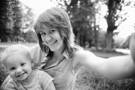 Black and white photo of happy family mother and her adorable toddler son at park making selfieの写真素材