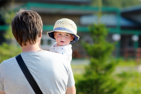 Middle age father with his toddler son walking outdoors at the hot summer dayの写真素材