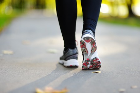 Runner feet running on road closeup on shoe. Woman fitness jog workout, welness conceptの写真素材
