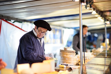 PARIS, FRANCE - NOVEMBER 22, 2015: A vendor selling cheese on Paris farmer agricultural marketの写真素材