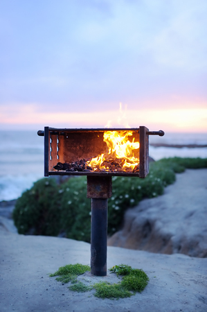 Fire in grill near ocean at the sunsetの写真素材