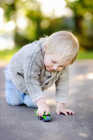 Cute toddler boy playing with toy car outdoors at warm summer dayの写真素材