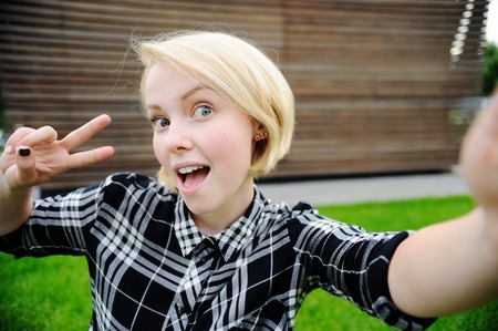 Young woman taking a outdoors self portrait (selfie) with smart phoneの写真素材