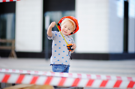 Portrait of cute little builder in hardhats with ruler working outdoorsの写真素材