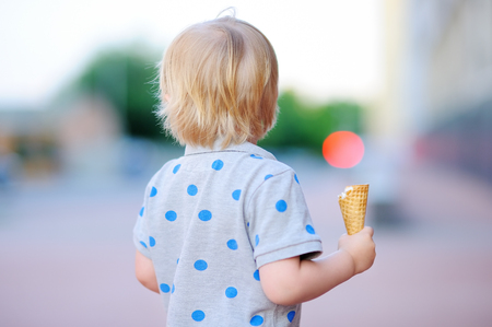 Cute toddler boy eating Ice-Cream in Cone outdoorsの写真素材