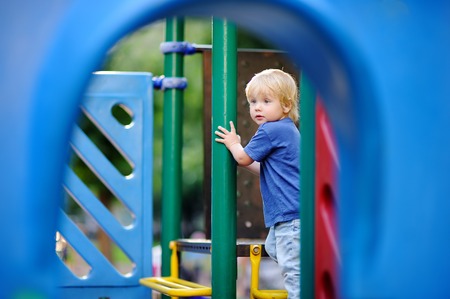 Cute toddler boy having fun on outdoors playground. Active game for little kidsの写真素材