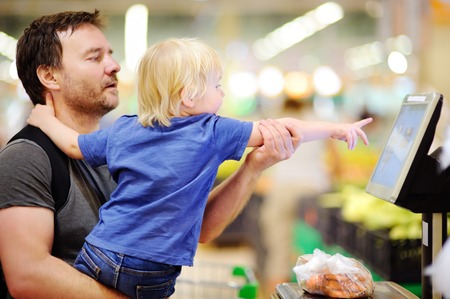 Cute toddler boy and his middle age father in a food store or a supermarket. Lifestyle of family with kidsの写真素材