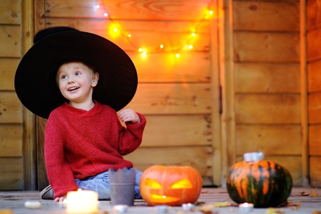 Cute little wizard playing with halloween pumpkins with lights on backgroundの写真素材