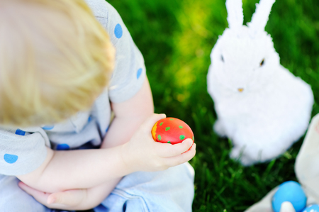Little boy hunting for easter egg in spring garden on Easter day. Cute little child with traditional bunny celebrating feastの写真素材