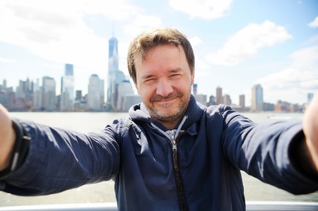 Middle age man making a self portrait (selfie) with Manhattan skyscrapers in New York Cityの写真素材