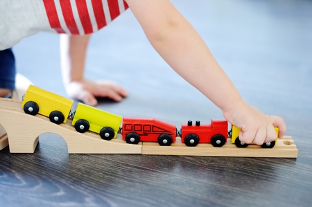 Close up photo of toddler boy playing with toy wooden train at home. Game for little childrenの写真素材