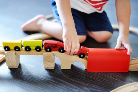 Close up photo of toddler boy playing with toy wooden train at home. Game for little childrenの写真素材