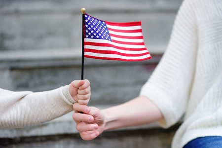 Young woman and little child holding american flag. Independence Day concept. Family togetherの写真素材
