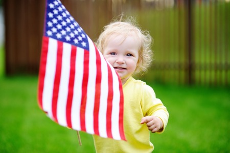 Cute toddler girl holding american flag. Independence Day concept.の写真素材