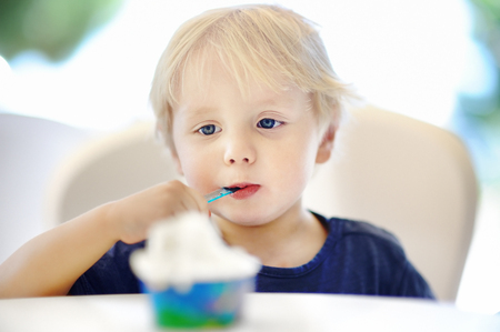Cute little boy eating Ice-Cream gelato in Italian indoors cafe. Sweets/sugar food for little kidsの写真素材