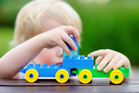 Toddler boy playing with toy train outdoors at warm summer day. Toys for little childrenの写真素材