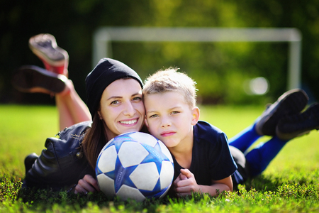 Young mother and her little boy playing a soccer game on sunny summer day. Family having fun with ball outdoorsの写真素材
