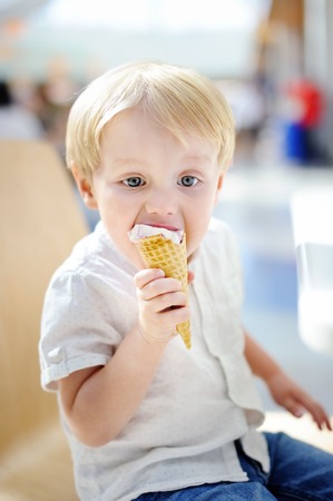 Cute little boy eating Ice-Cream gelato in Italian indoors cafe. Sweets/sugar food for little kidsの写真素材