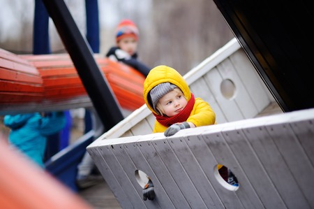 Happy little boy having fun on outdoor playground. Spring and autumn active leisure for kids.