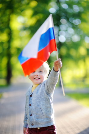 Cute little boy holding russian flag during walking in summer parkの写真素材