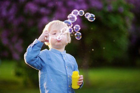 Cute little boy blowing soap bubbles in beautiful summer park. Active leisure for toddler childの写真素材