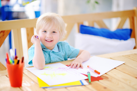 Cute little boy drawing and painting with colorful markers pens at kindergarten. Creative kid painting at playschool. Development toys for preschooler childrenの写真素材
