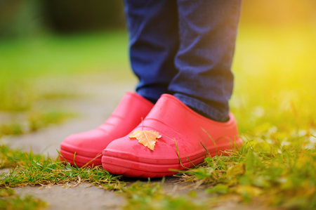 Close up photo of woman legs in rubber shoes. People in autumn.の写真素材