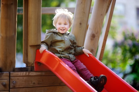 Happy little boy having fun on outdoor playground. Autumn/fall or spring active sport leisure for kidsの写真素材