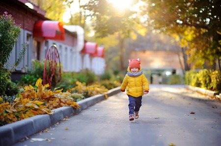 Cute toddler boy playing outdoors at autumn day. Happy little child running home after kindergartenの写真素材